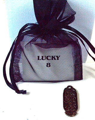 Wolf Moon Azure Lucky 8 amulet for good fortune. Ornate bronze amulet beside black organza pouch labeled LUCKY 8