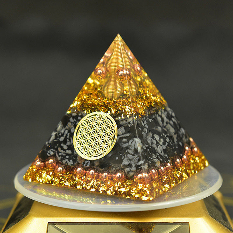 Reiki orgonite pyramid with golden accents and flower of life symbol for energy healing